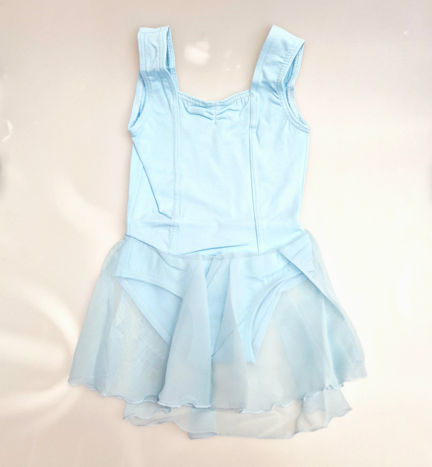 Body danza classica smanicata per bambina in cotone elastico, con gonnellino in chiffon e dettaglio microfibra foderata sul petto.