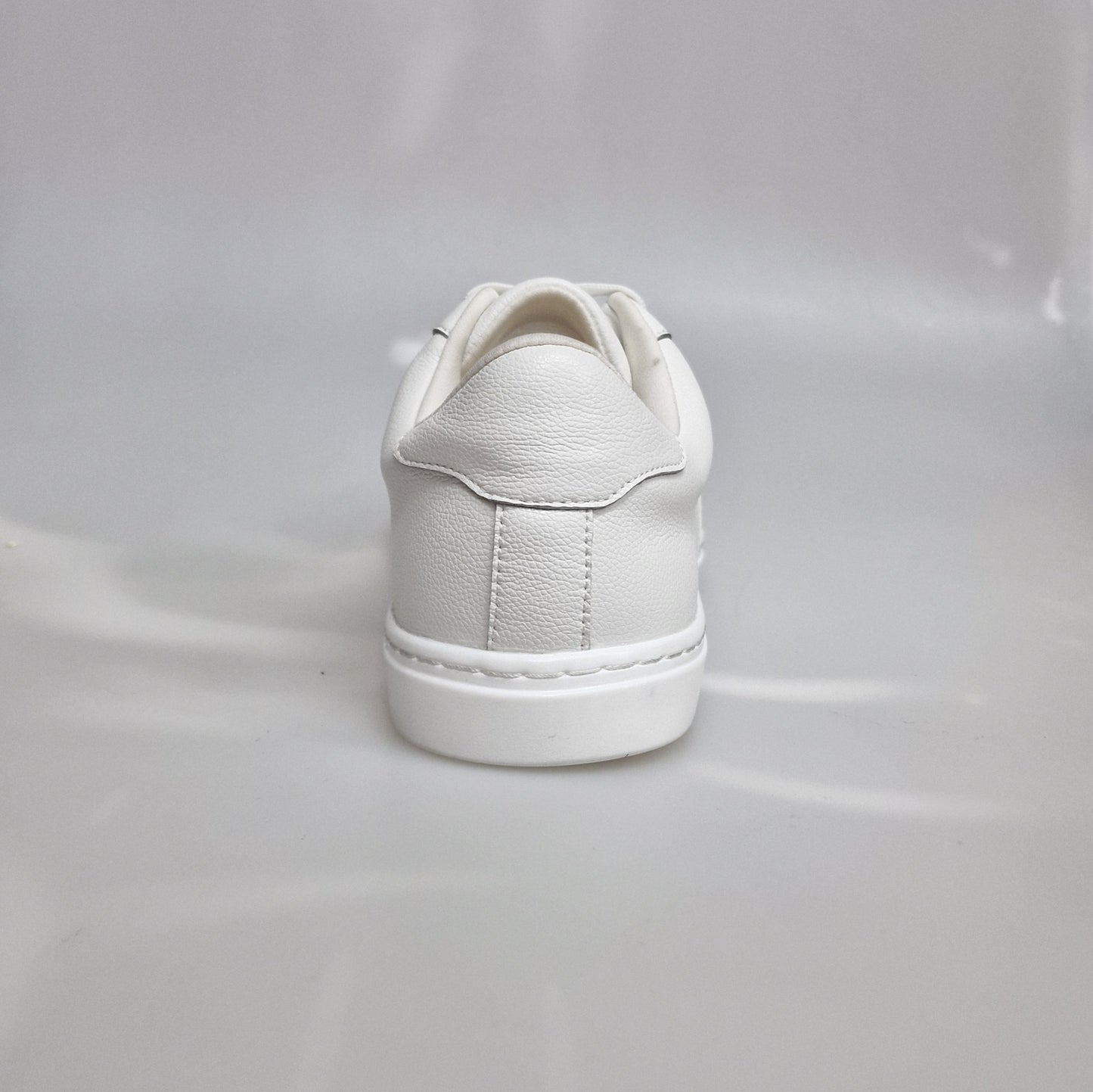 Scarpa sneaker in ecopelle bianca vegan con suola bianca in gomma e resina, dettagli neri e design moderno.