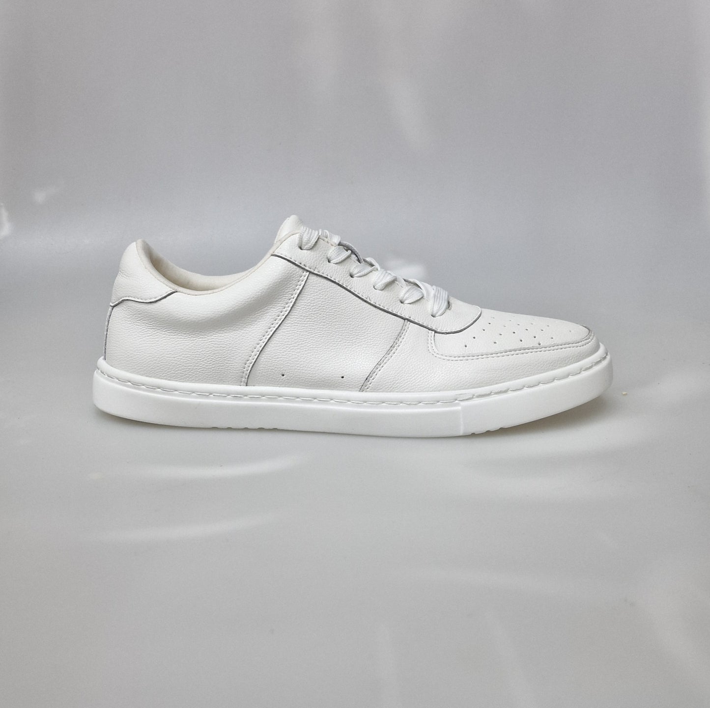 Scarpa sneaker in ecopelle bianca vegan con suola bianca in gomma e resina, dettagli neri e design moderno.